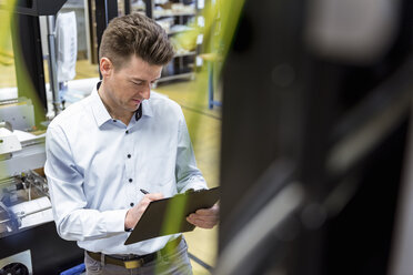 Man with clipboard in factory taking notes - DIGF03980