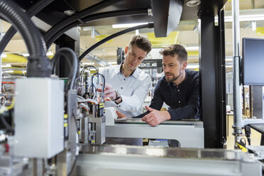 Two men examining machine in factory - DIGF03981