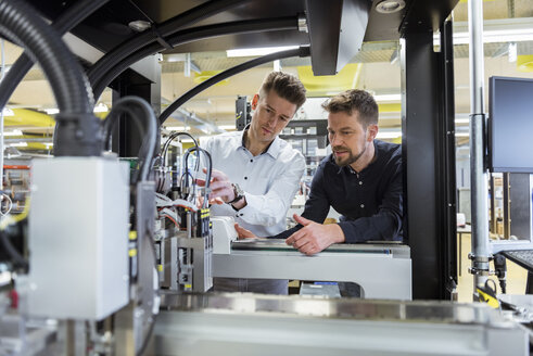 Zwei Männer untersuchen eine Maschine in einer Fabrik - DIGF03981