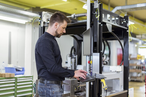 Mann in Fabrik, der eine Maschine bedient - DIGF03982