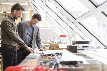 Two smiling businessmen looking at plan in factory - DIGF03994