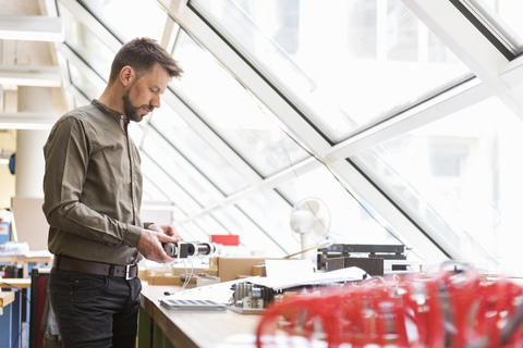 Mann in Fabrik, der das Produkt prüft, lizenzfreies Stockfoto