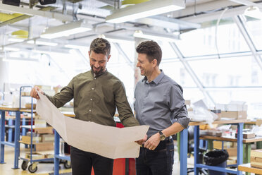 Two smiling men looking at plan in factory - DIGF04007