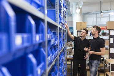 Two men talking in factory storeroom - DIGF04019