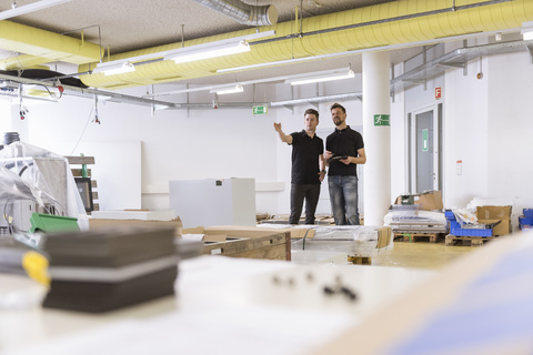 Zwei Männer unterhalten sich in einer Fabrik, lizenzfreies Stockfoto