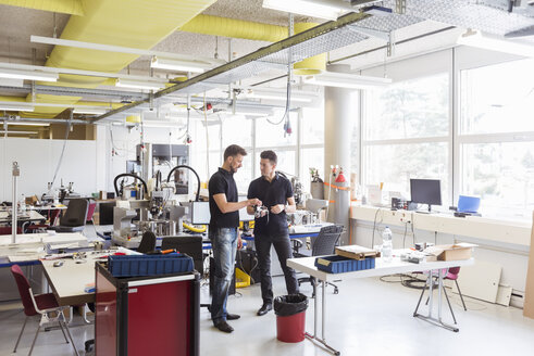 Zwei Männer sprechen über ein Produkt in einer Fabrik - DIGF04025