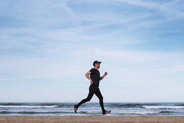 Spanien, schwarz gekleideter Mann beim Joggen am Strand - RTBF01223