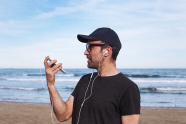 Mann mit Smartphone und Kopfhörern am Strand - RTBF01224