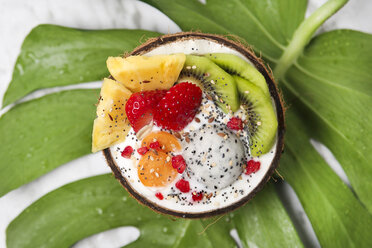 Kokosnussschale mit verschiedenen Früchten, Naturjoghurt und Samen auf Blatt - RTBF01226