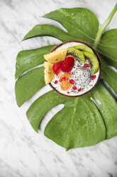 Coconut bowl with variuos fruits, natural yoghurt and seeds on leaf - RTBF01227