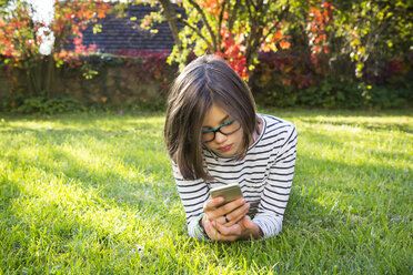 Girl lying on meadow using smartphone - LVF06912