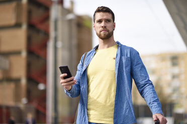 Junger Mann mit Smartphone am Bahnhof - JSMF00157