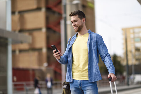 Junger Mann mit Smartphone am Bahnhof - JSMF00158