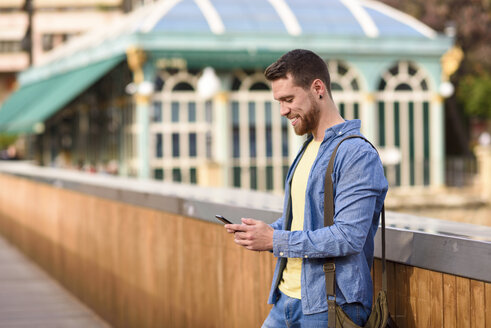 Junger Mann schaut auf sein Smartphone - JSMF00165