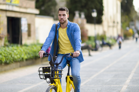 Junger Mann mit Leihfahrrad in der Stadt, lizenzfreies Stockfoto