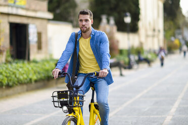 Young man riding rental bike in the city - JSMF00171