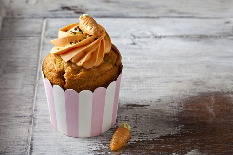 Karotten-Cupcake garniert mit Sahnehaube, Zuckergranulat und Marzipankarotte, lizenzfreies Stockfoto