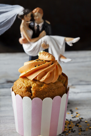 Carrot cup cake garnished with cream topping, sugar granules and marzipan carrot stock photo