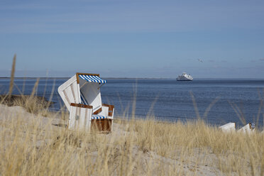 Germany, Schleswig-Holstein, Sylt, List, empty hooded beach chair, cruise ship in the background - WIF03505