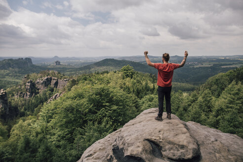 Deutschland, Sachsen, Elbsandsteingebirge, Wanderer steht auf einem Felsen und jubelt - GUSF00734