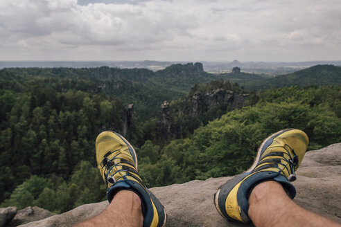 Deutschland, Sachsen, Elbsandsteingebirge, Männerfüße bei einer Wanderung auf einem Felsen sitzend - GUSF00736