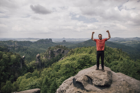 Deutschland, Sachsen, Elbsandsteingebirge, Wanderer steht auf einem Felsen und jubelt - GUSF00737