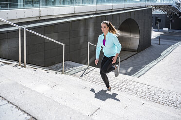 Junge Frau läuft auf einer Treppe in der Stadt - DIGF04034