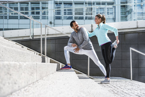 Couple doing stretching exercise on stairs in the city - DIGF04036