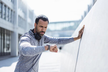 Man having a break from exercising looking on smartwatch - DIGF04053