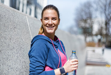 Lächelnde junge Frau, die eine Pause vom Sport macht - DIGF04058