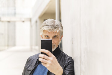 Älterer Mann macht Selfies mit seinem Smartphone - FMKF05033