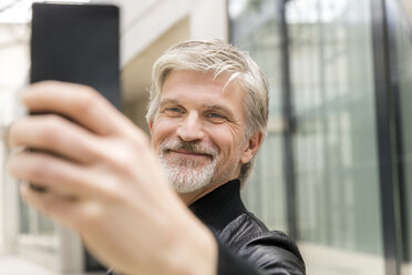 Mature man taking selfies with his smartphone - FMKF05034