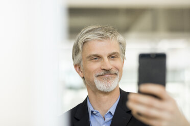 Mature man taking selfies with his smartphone - FMKF05052