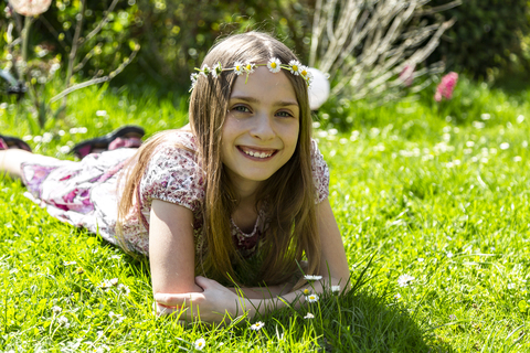 Porträt eines glücklichen Mädchens auf einer Wiese im Garten liegend, lizenzfreies Stockfoto