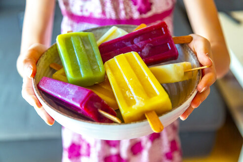 Girl holding bowl with colorful popsicles - SARF03700