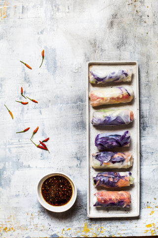 Vegan rice paper wraps (vietnamese summer rolls), filled with cabbage, carrots, bell pepper, rice noodles, and dipping sauce stock photo