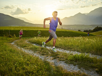 Athleten laufen bei Sonnenuntergang auf dem Feldweg - CVF00331