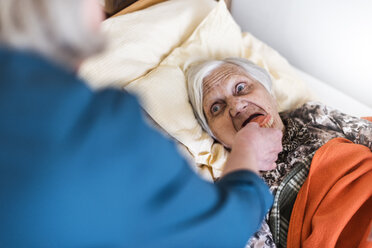 Woman taking care of old woman lying in bed - DIGF04064