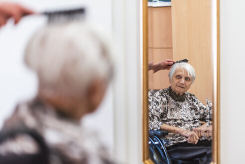 Frau kümmert sich um alte Frau beim Bürsten ihrer Haare - DIGF04067