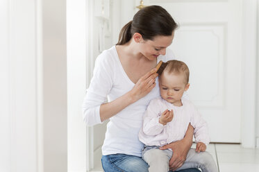 Mother brushing baby's hair at home - DIGF04077