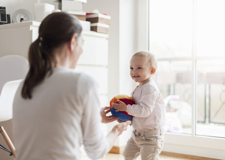 Mutter und Baby spielen mit einem Ball zu Hause - DIGF04078