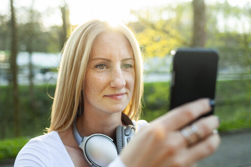 Porträt einer blonden Frau, die ein Selfie mit ihrem Smartphone macht - NAF00094
