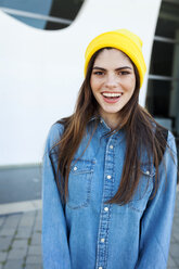 Portrait of laughing young woman wearing yellow cap - VABF01555