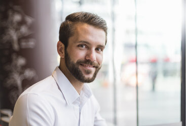 Portrait of smiling young businessman at the window - DIGF04079