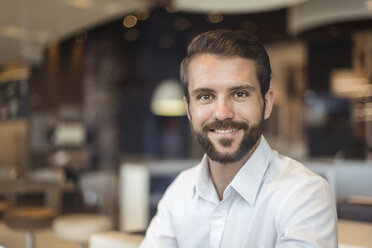 Portrait of smiling young businessman in a cafe - DIGF04082