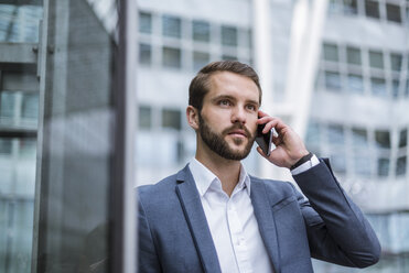 Young businessman on cell phone looking sideways - DIGF04094