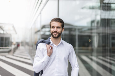 Portrait of smiling young businessman at glass facade - DIGF04101