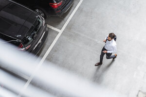 Young businessman with backpack on the go at parking garage - DIGF04110