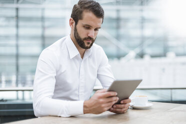 Young businessman using tablet in a cafe - DIGF04115