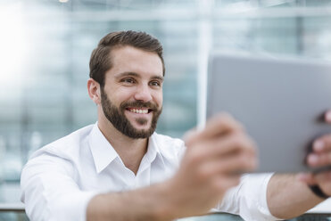 Lächelnder junger Mann macht ein Selfie mit Tablet - DIGF04117